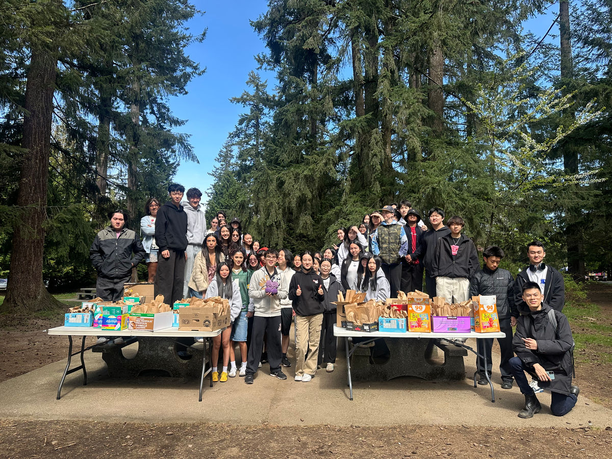 A large group of volunteers behind tables of finished care packages at an outdoor distribution